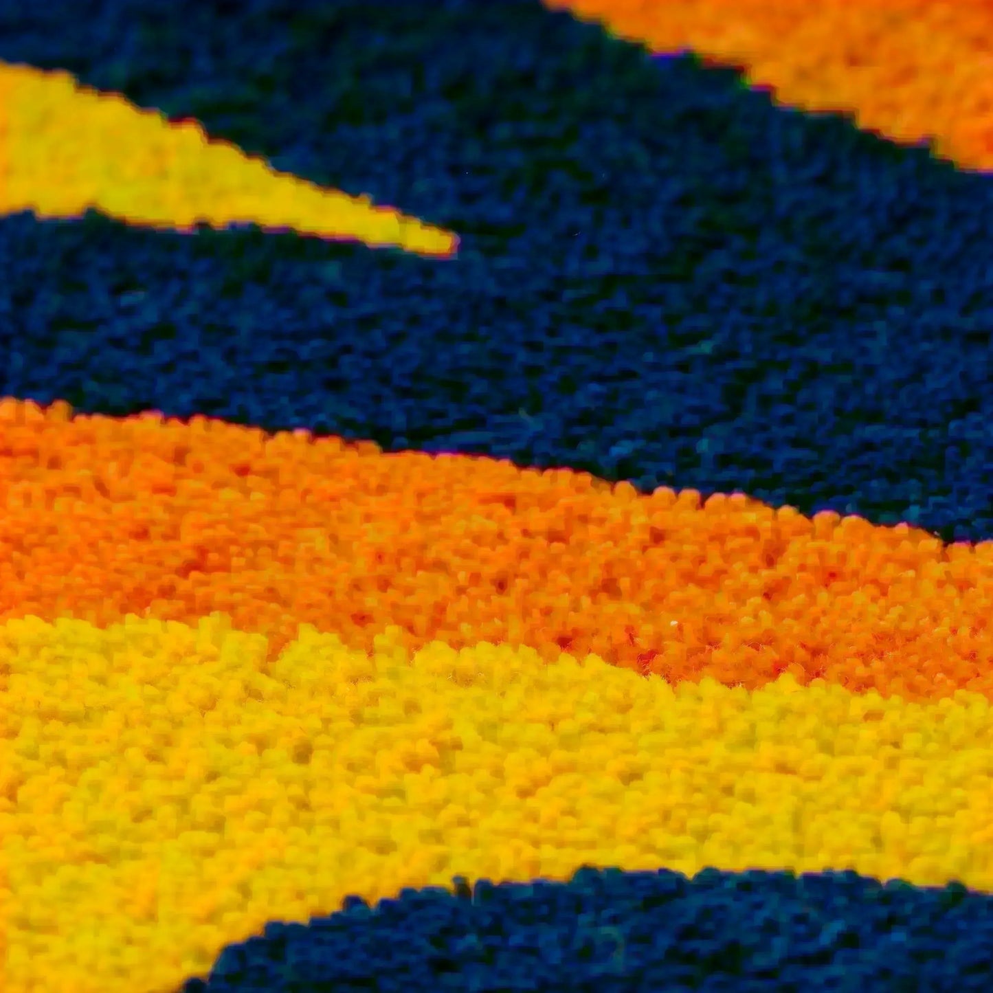 オレンジ、黄色、ネイビーの3色を使用した大胆なタフティングラグのクローズアップショット。鮮やかなカラーコントラストと滑らかな質感が印象的