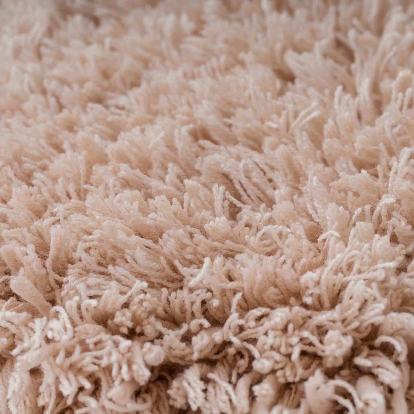 ベージュカラーのタフティングラグのクローズアップショット。柔らかい毛足が密集しており、ボリューム感のある仕上がり。繊維が均一で滑らかな触り心地を表現している