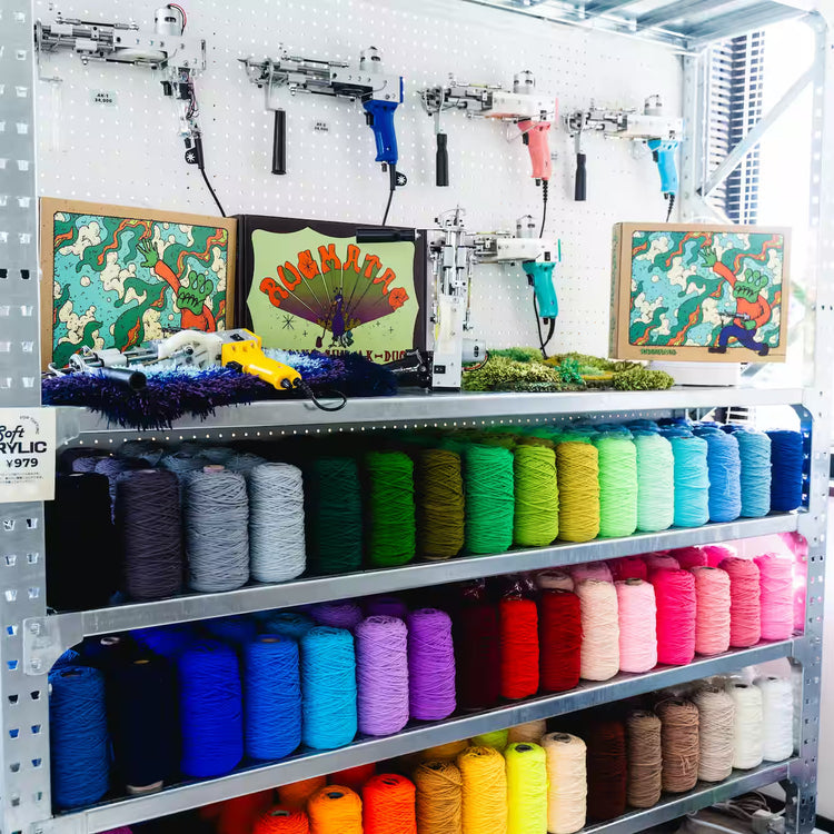 壁に掛けられたカラフルなタフティングガンと、その下に飾られたアートボードやマット