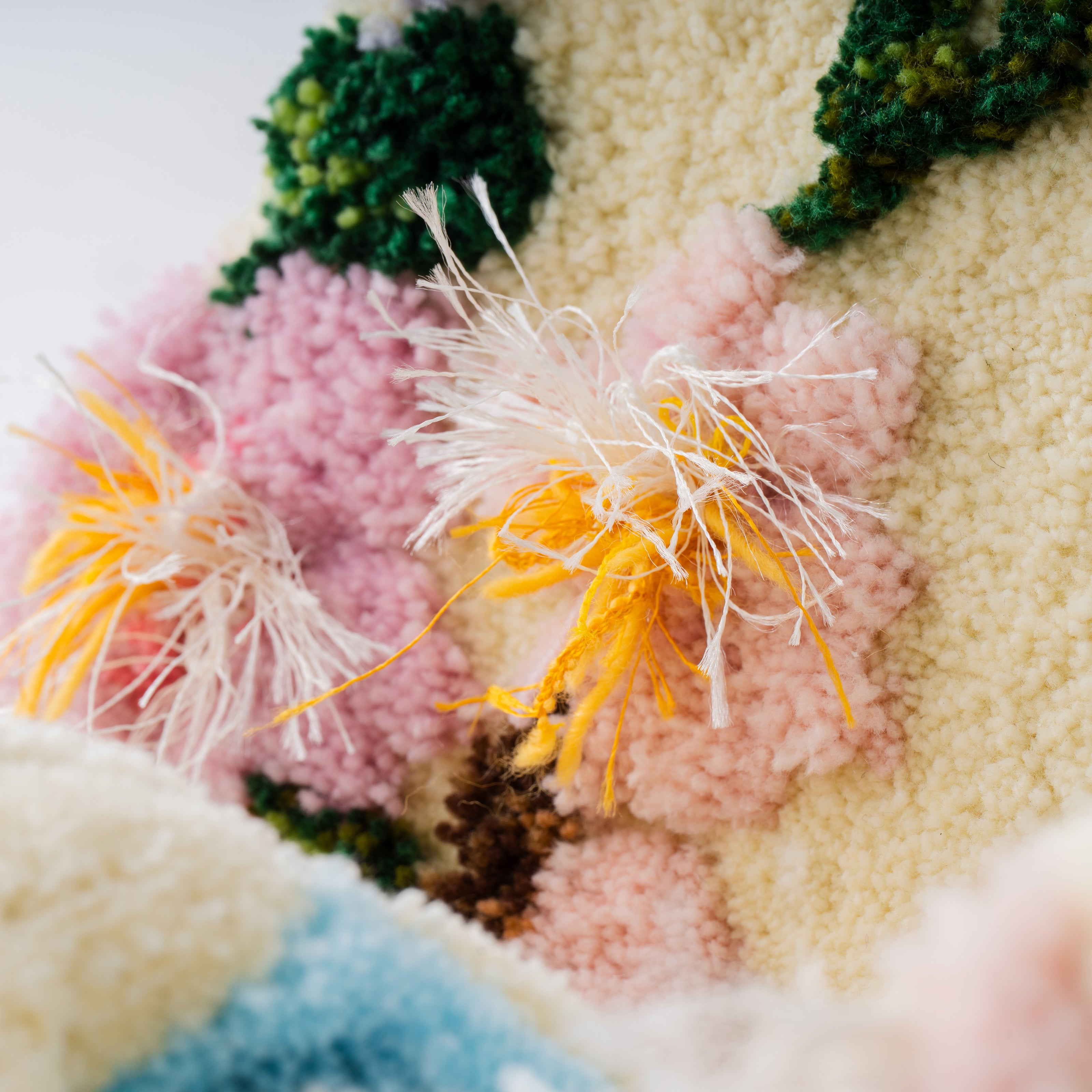 タフティングで作られた折り鶴の花モチーフ部分の接写。黄色やピンクの毛糸が立体的に広がり、繊細な刺繍のような質感を持つディテール。RUGMATAGの細密な毛糸表現が感じられる一枚。
