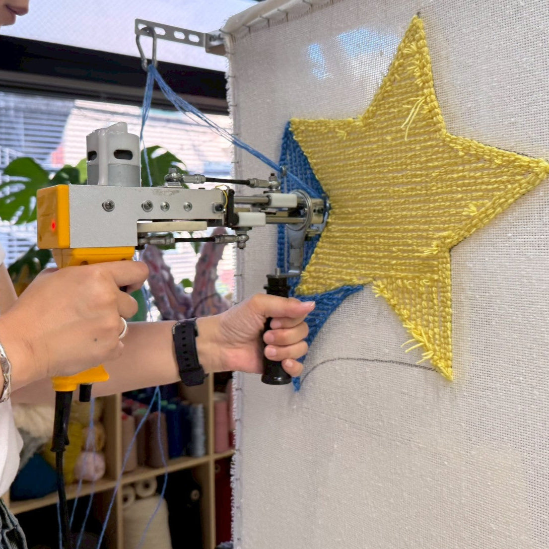 黄色い星型のラグをタフティングガンで打ち込んでいる。