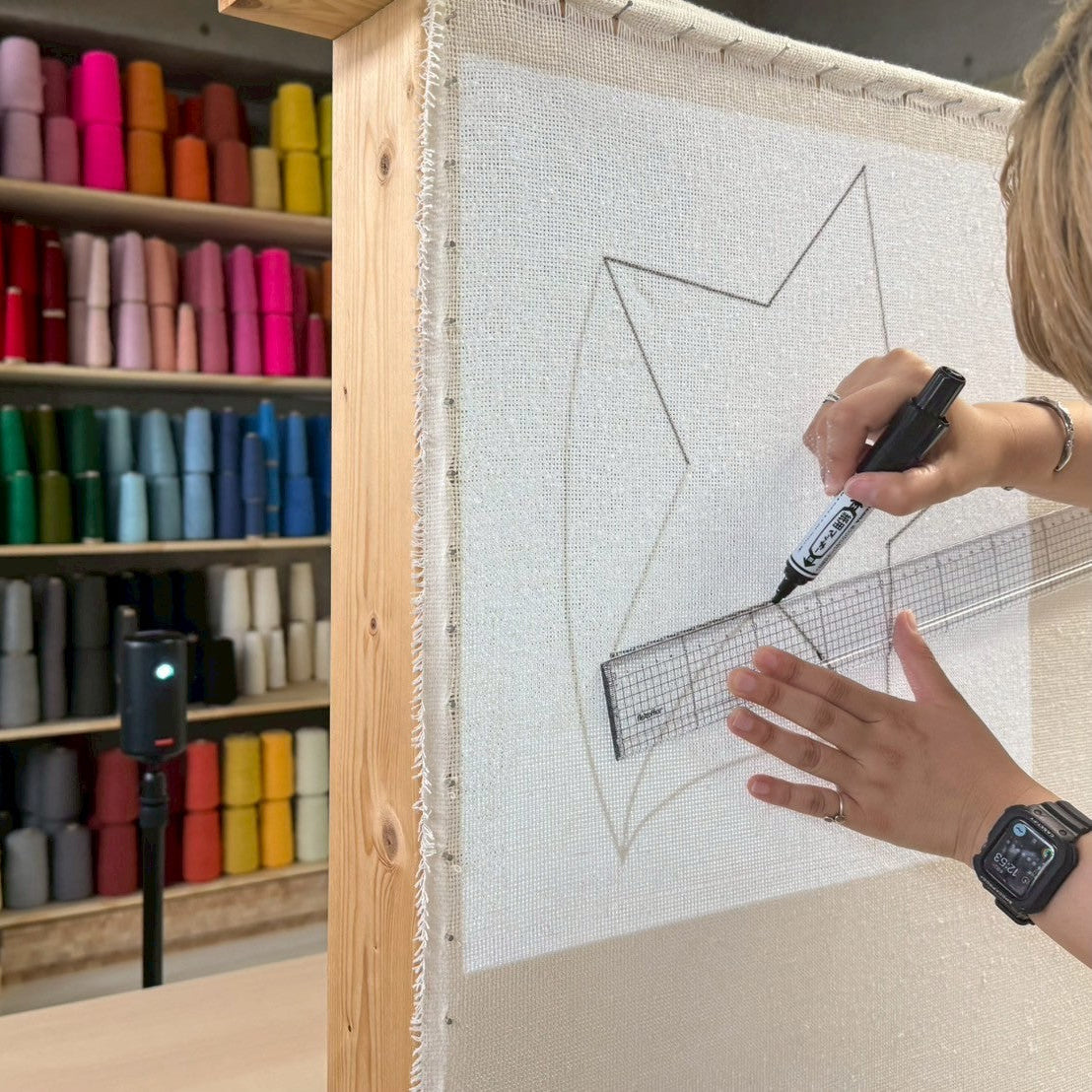 基布に星型の図案を定規とペンで下書きしている。