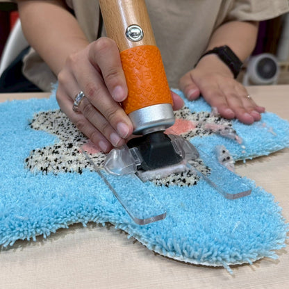 水色ベースの花型ラグをバリカンでフラットに刈っている。