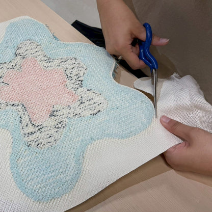 花形のタフティングラグ裏面をハサミで余分な基布をカットしている。