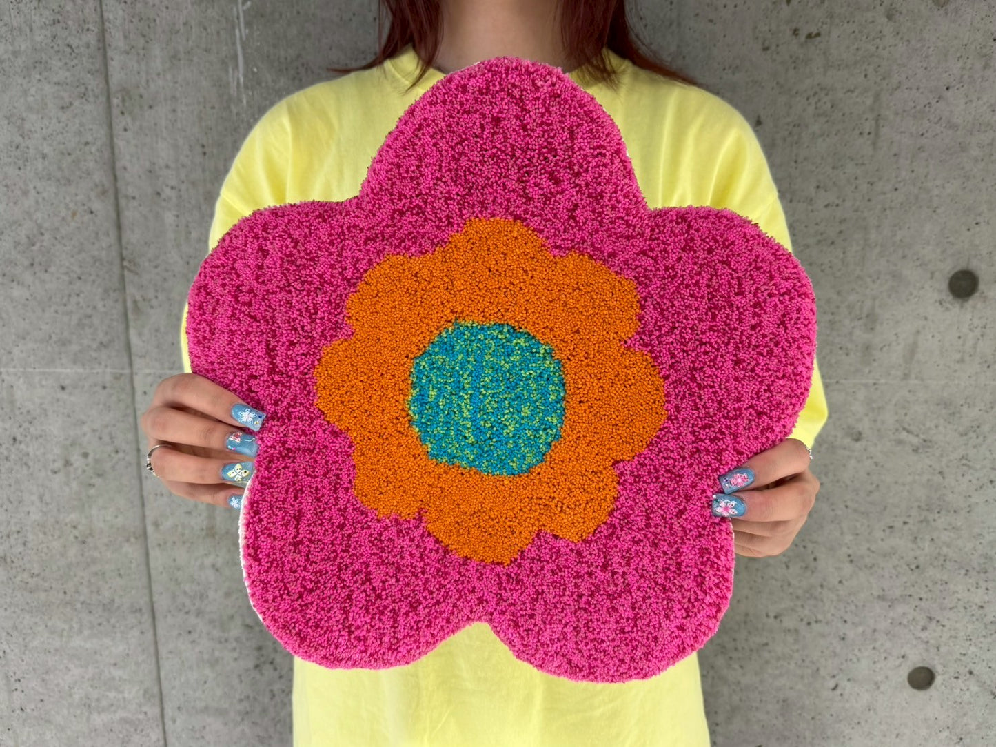 人物が手に持った花型のタフティングラグ。チェア&アートラグコース タフティングワークショップ 大阪北堀江