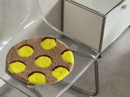 透明な椅子に置かれた円形のタフティングラグ。茶色のベースに明るい黄色の水玉模様がデザインされている。チェア&アートラグコース タフティングワークショップ 大阪北堀江