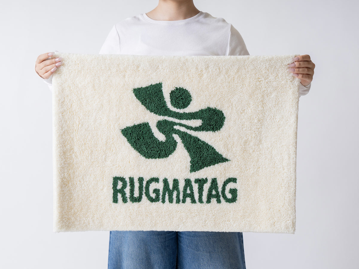 RUGMATAGロゴ入り長方形タフティングラグを両手で掲げる